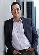 A man in a suit leaning against a wall.
